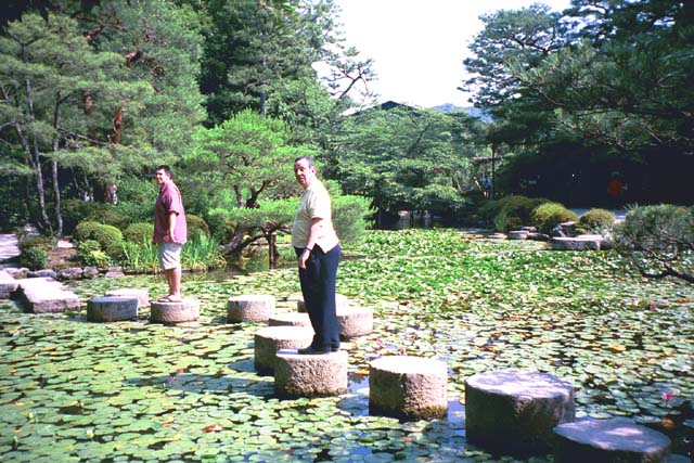 Joe and Sam on stepping stones across lily pond at Heian Shrine